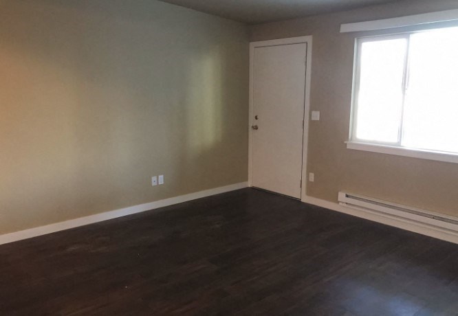 an empty living room with wooden floors and a door