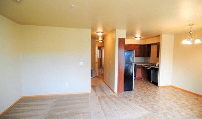 an empty living room and kitchen with a wood floor