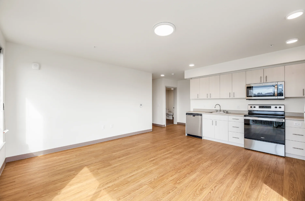 an empty kitchen with white cabinets and a wood floor