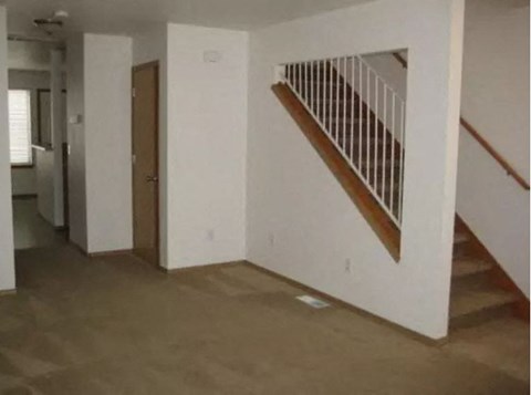 an empty room with a staircase and a hallway with a door