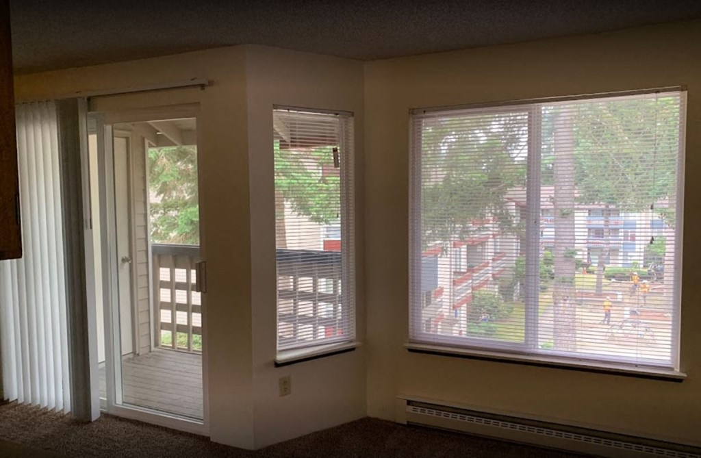 a living room with large windows and a door to a balcony