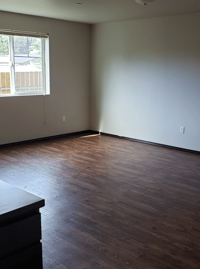 an empty living room with wood floors and a window