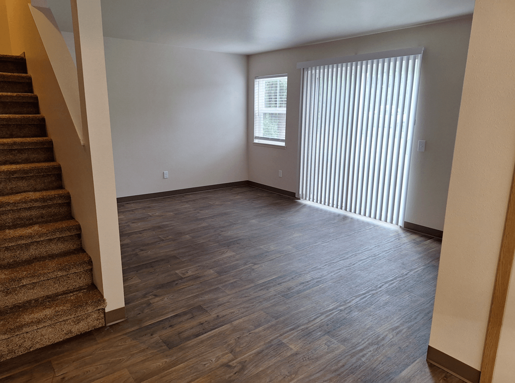 an empty living room with wood floors and a staircase