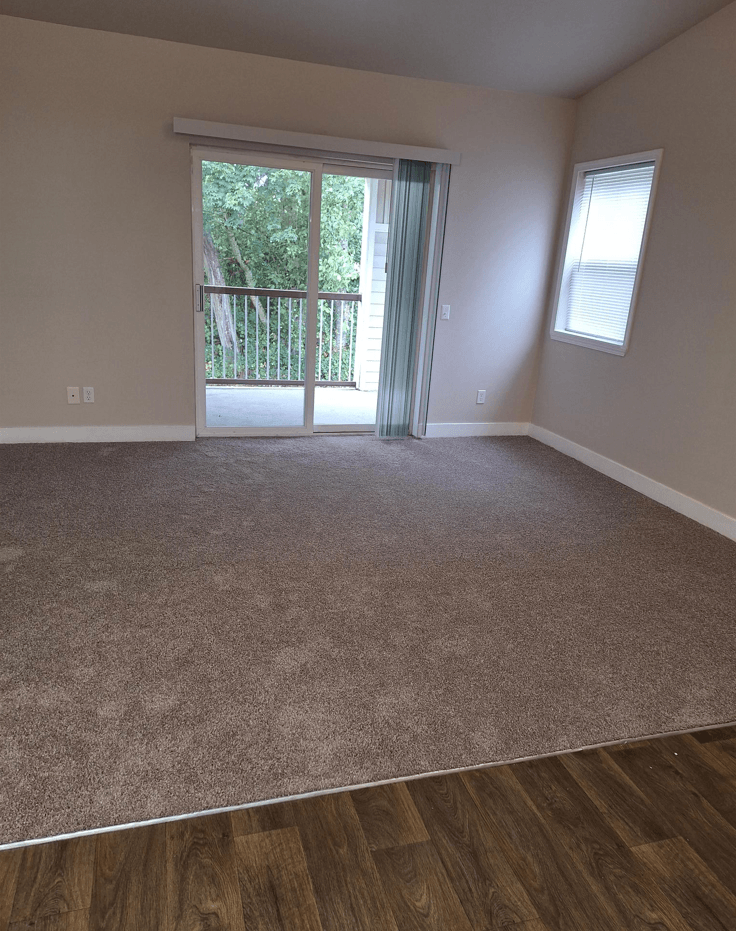 an empty living room with a door to a balcony