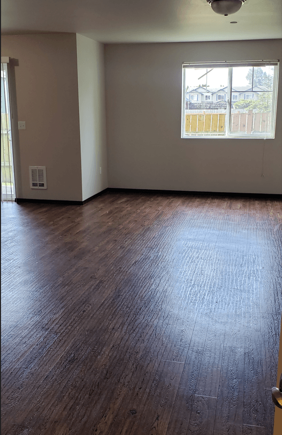 an empty living room with wood floors and a window