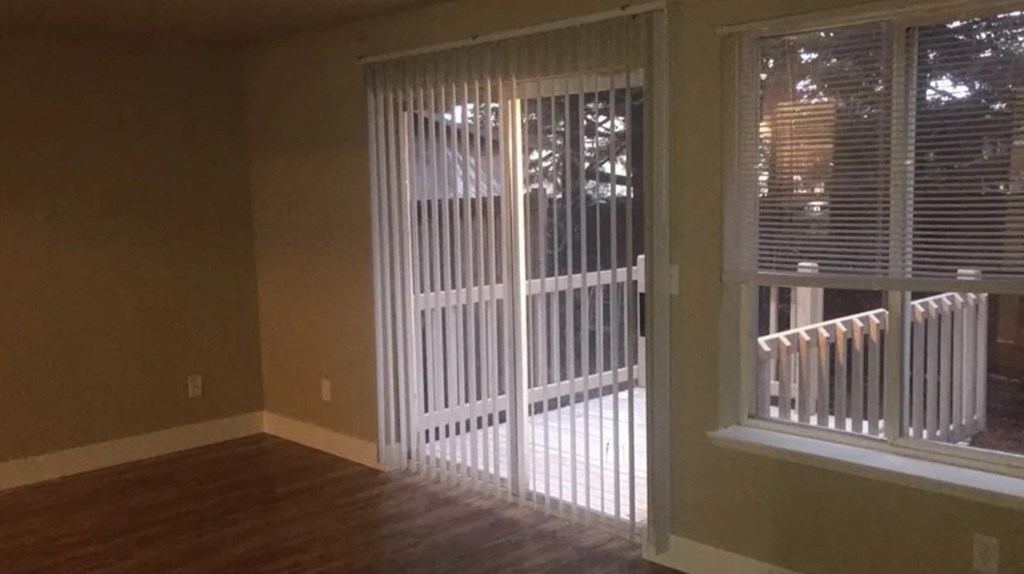 an empty living room with a sliding glass door to a patio