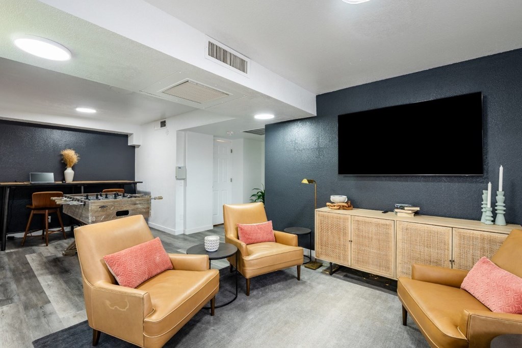A living room with two tan chairs and a black wall.