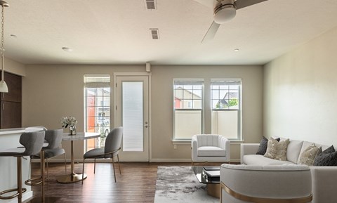 A modern living room with a grey sofa, a white table, and a ceiling fan.