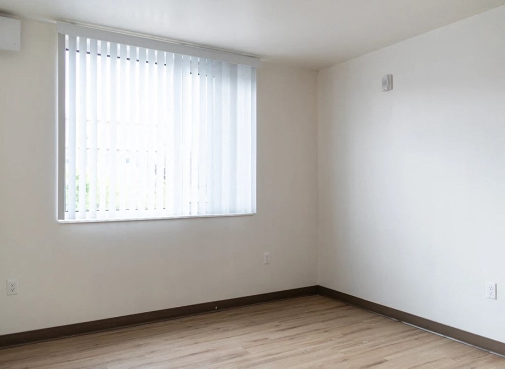A room with a window covered by white blinds.