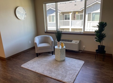 A living room with a chair, a table with a vase, and a window.