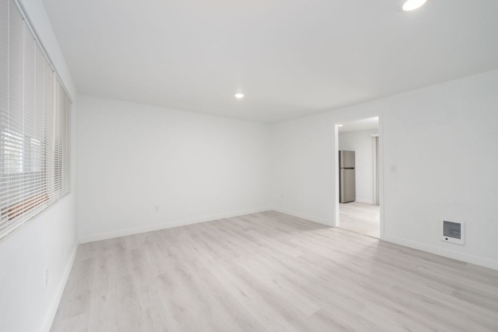 A room with a wooden floor and a door in the background.