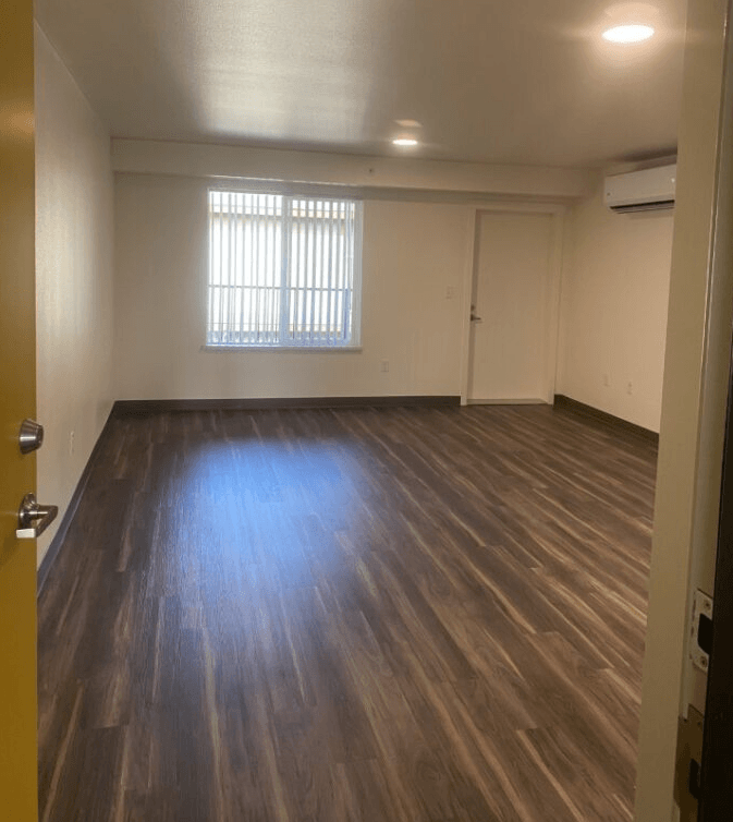 an empty living room with wooden floors and a window