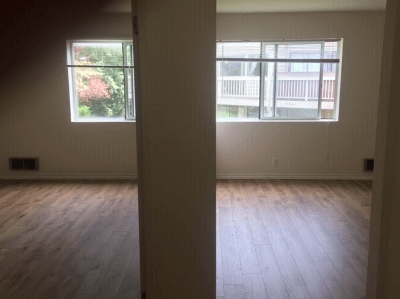 an empty living room with wood floors and a window