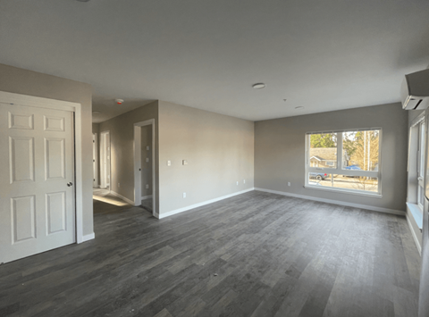 an empty living room with wood floors and a window