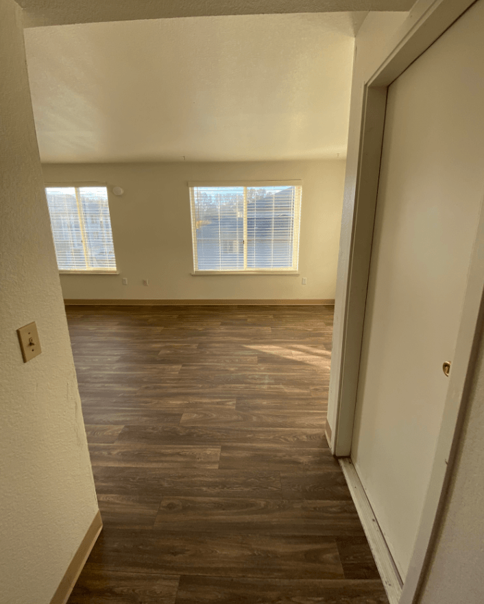 an empty living room with wood flooring and a large window