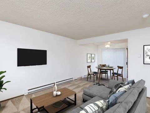 A living room with a grey couch, a wooden coffee table, and a dining table with chairs.