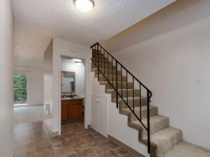 A staircase with a metal railing leads up to a bathroom.