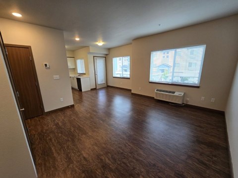A spacious room with wood flooring and a window.