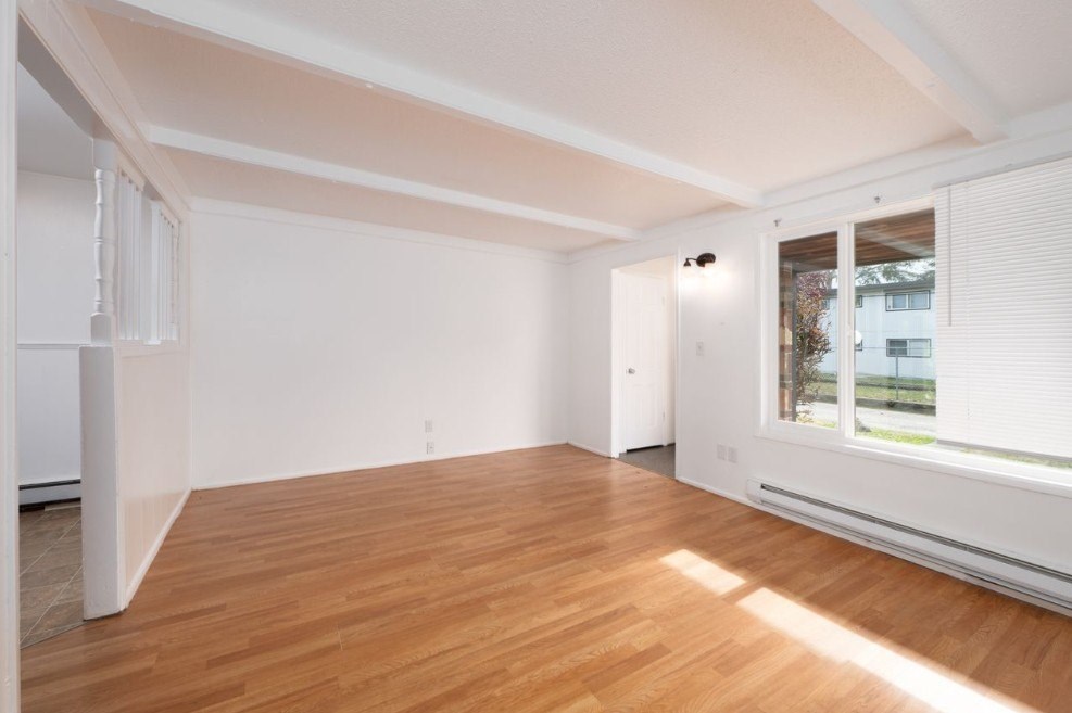 A room with wooden flooring and white walls.