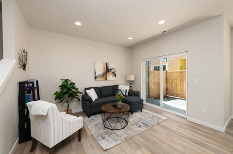 A living room with a white chair, a grey couch, a coffee table, and a painting on the wall.