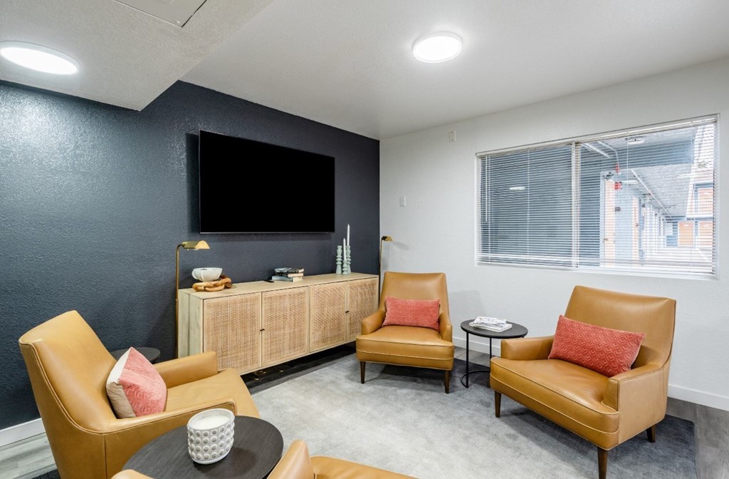 A living room with a black screen tv and brown leather chairs.