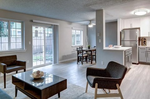 A modern living room with a glass coffee table and a chair.