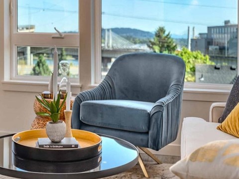 A blue striped armchair sits in a living room with a table in front of it.