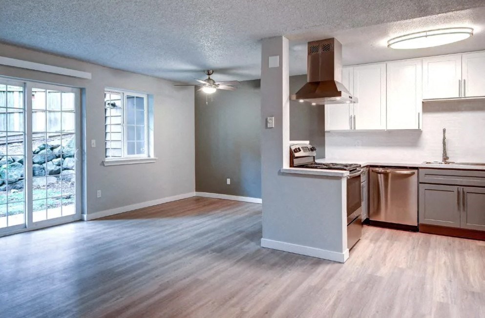 A kitchen with a stainless steel refrigerator and a wooden floor.