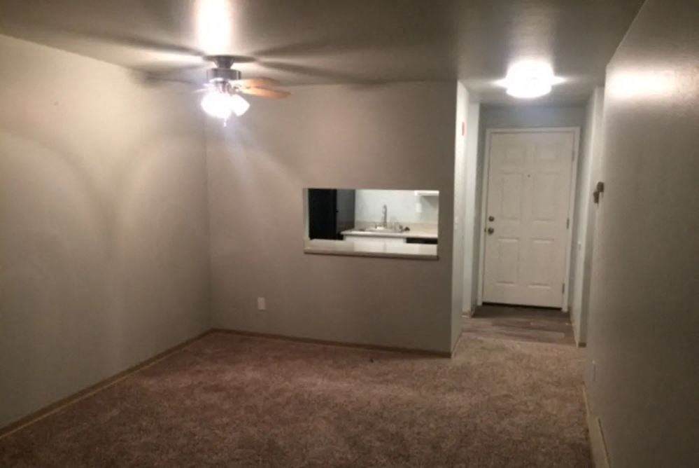 a empty living room with a ceiling fan and a sink