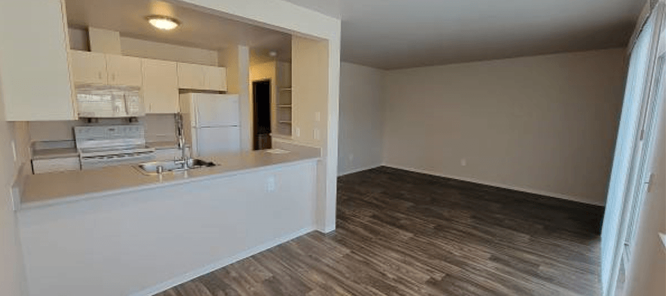 an empty room with a kitchen and a living room