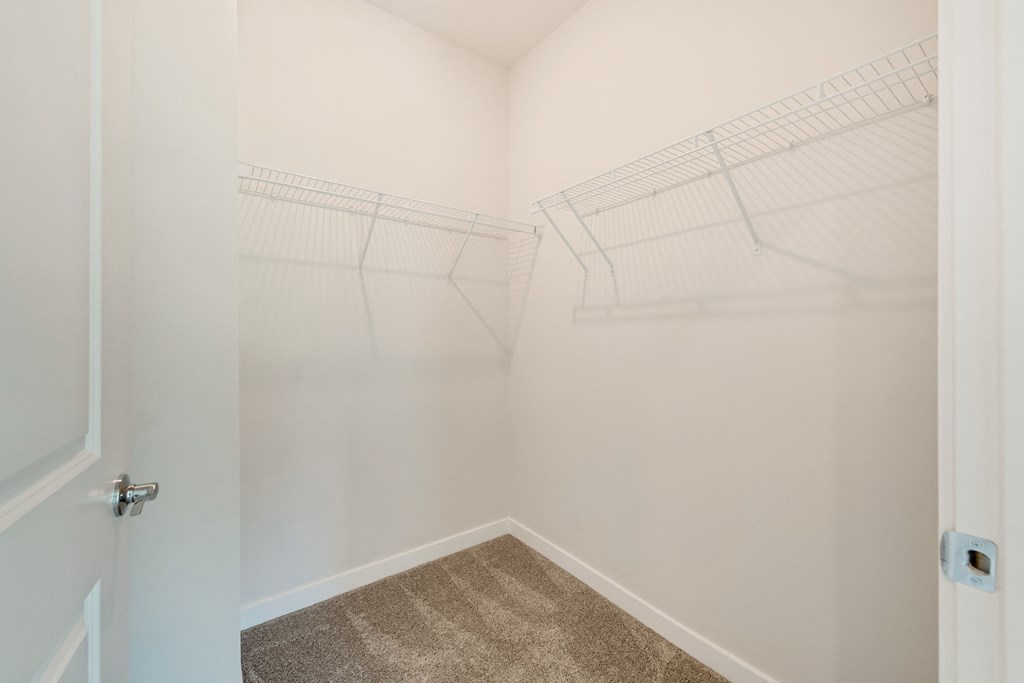 an empty closet in a home with white walls and carpet