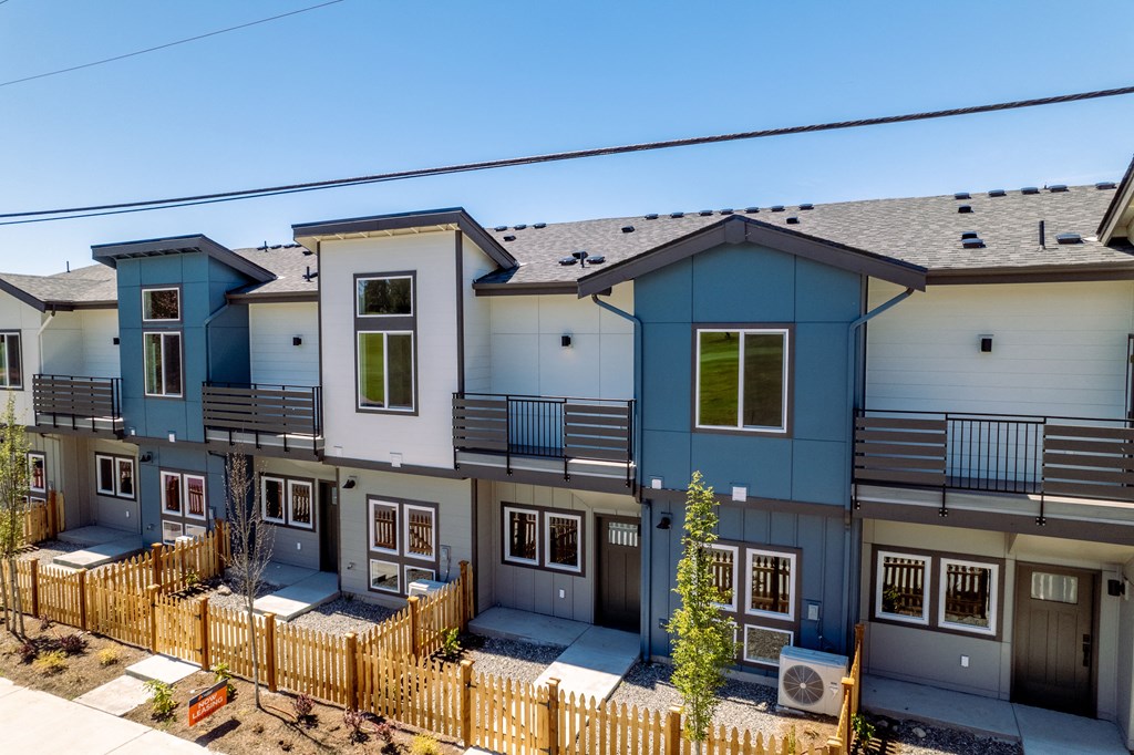 a row of blue and white apartments with a wooden fence