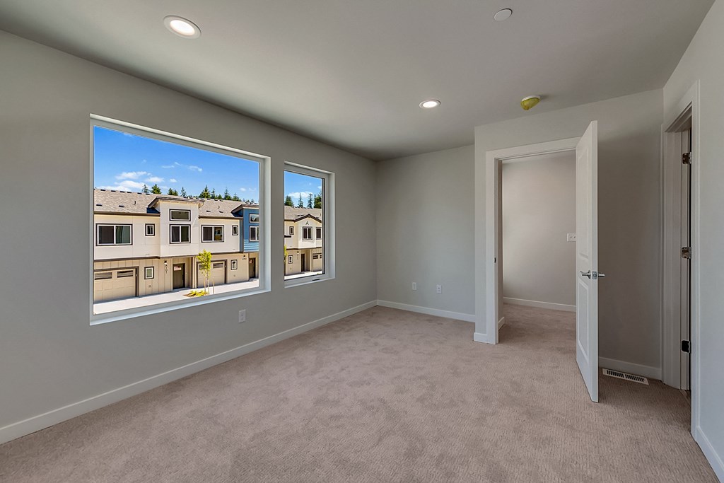 A room with a carpeted floor and a view of a building through the windows.