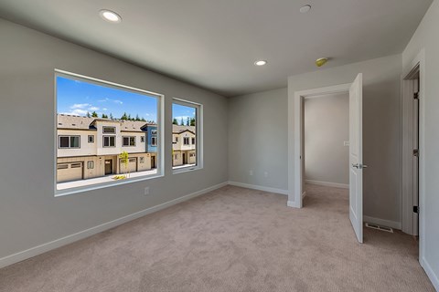 A room with a carpeted floor and a view of a building through the windows.