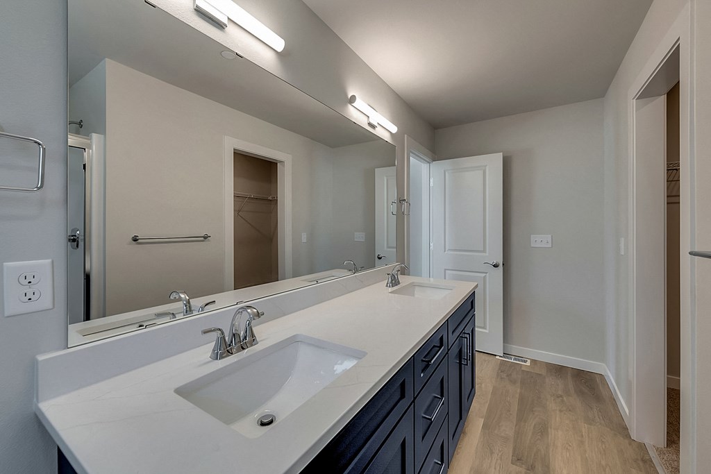 A bathroom with a white sink and a large mirror.