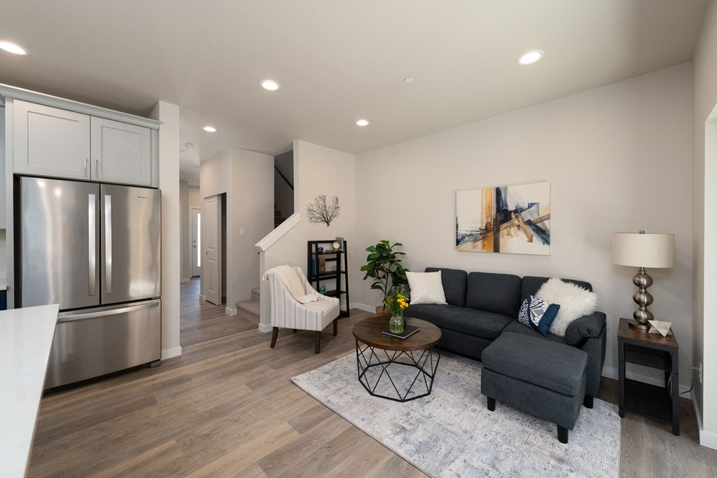 A modern kitchen with a stainless steel refrigerator and a grey sofa with a white throw pillow.