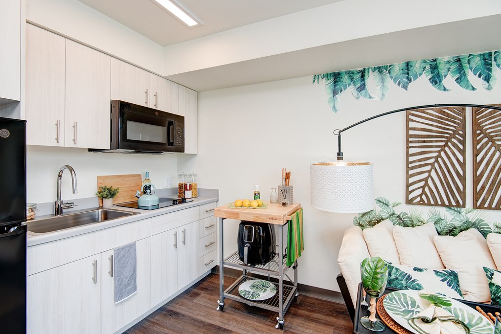 a small kitchen with a sink and a counter and a living room with a couch