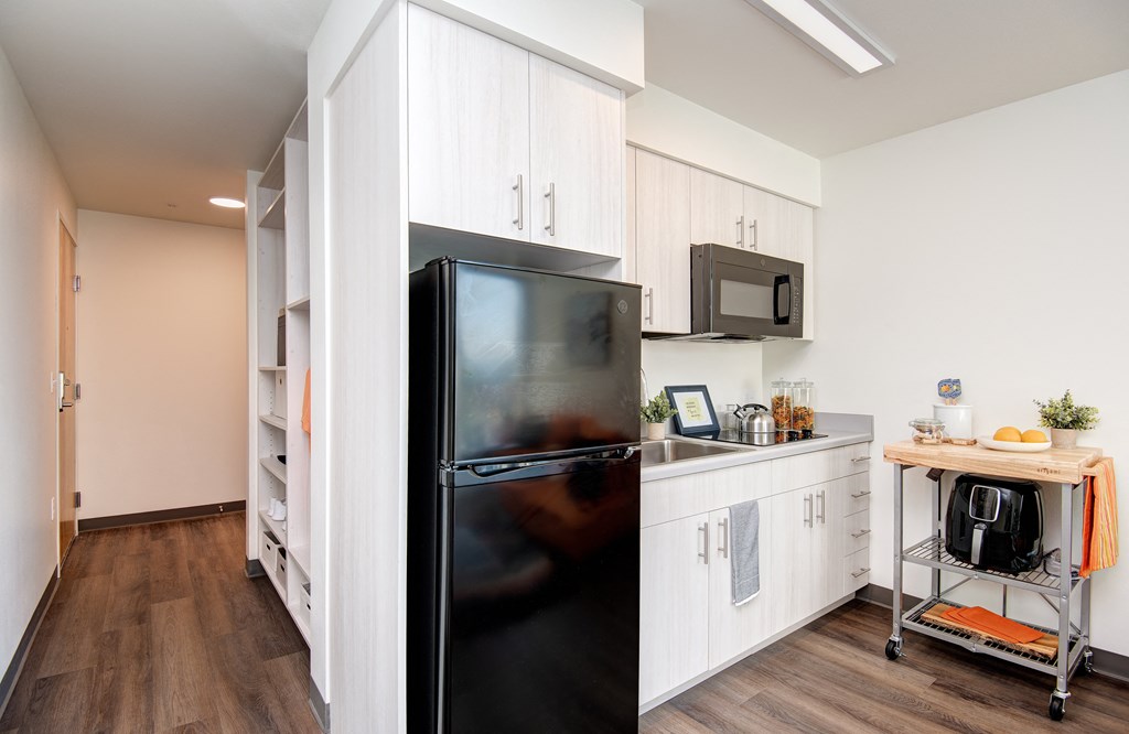 a kitchen with white cabinets and a black refrigerator
