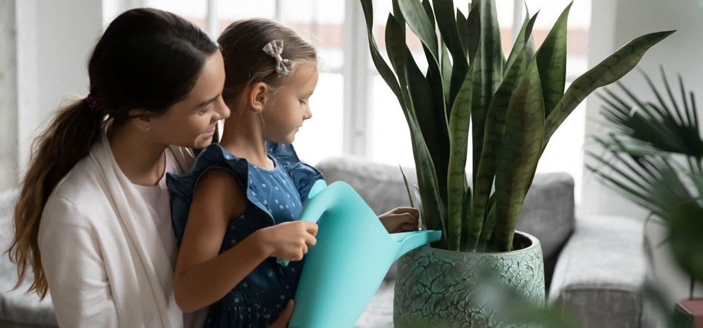 a mother and daughter looking at a plant in a room