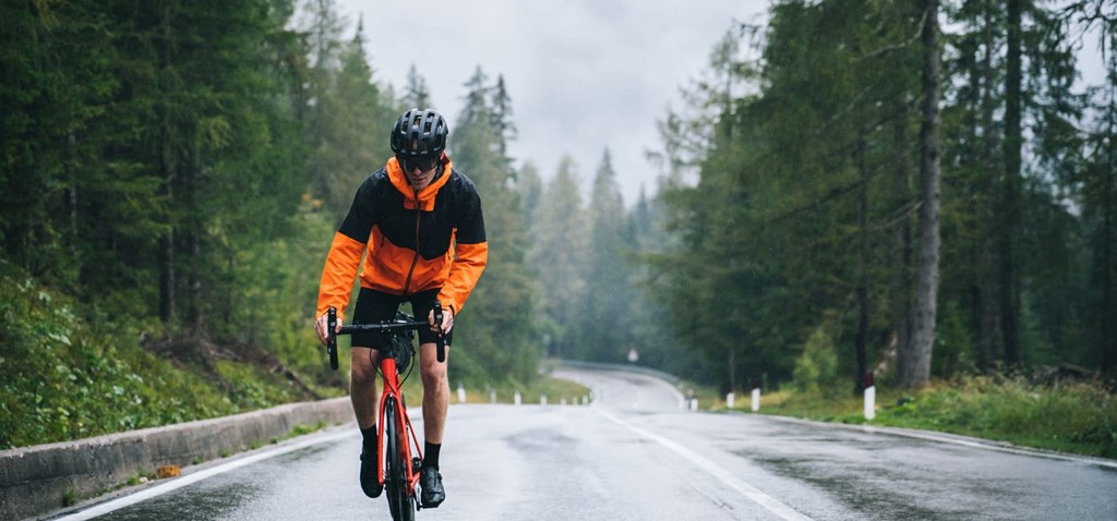 a man riding a bike down a road in the rain
