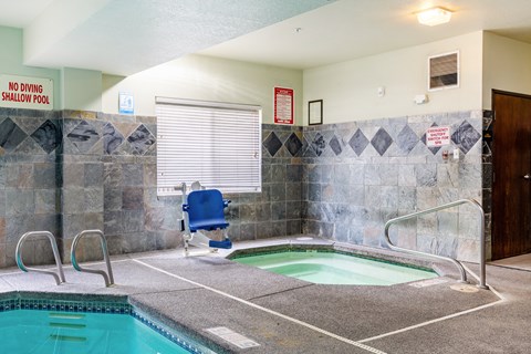 A small indoor pool with a blue chair and a sign that says "No Diving Shallow Pool.".