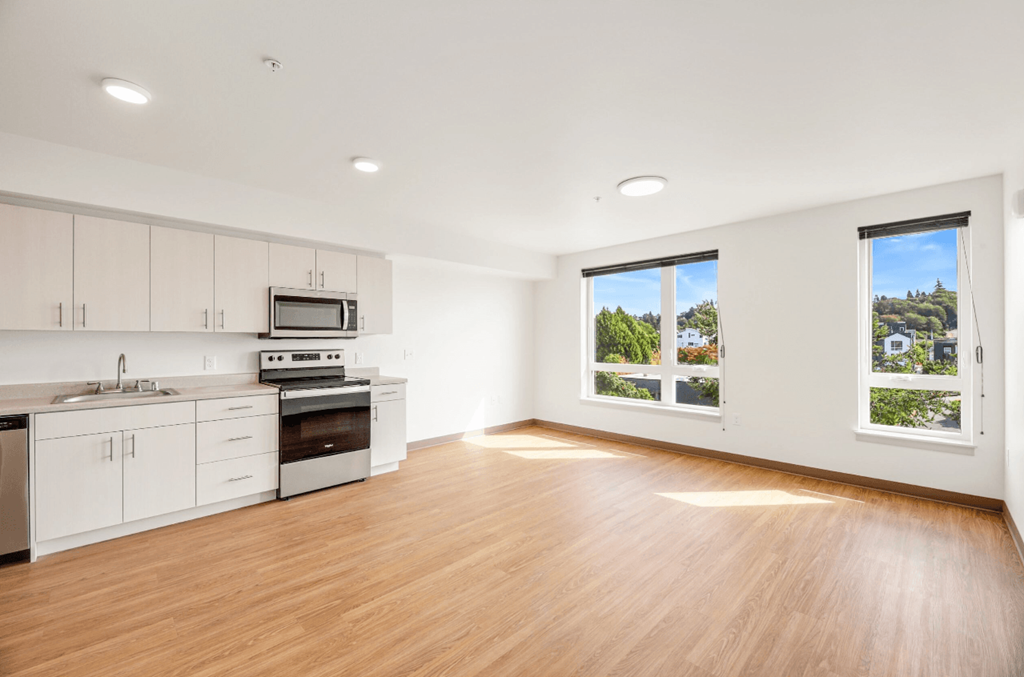 an empty kitchen with white cabinets and a large window