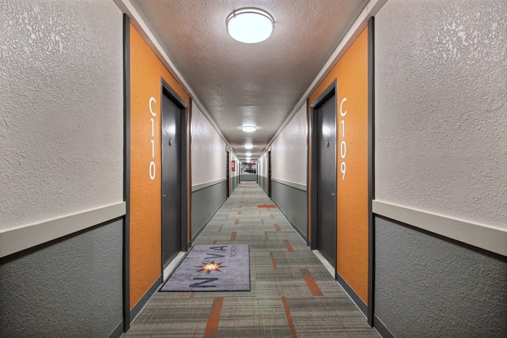 a long hallway with orange doors and a rug in the middle