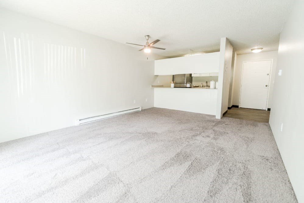 an empty living room with white walls and a ceiling fan