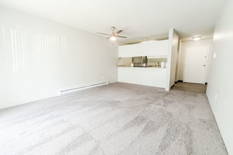 an empty living room with white walls and a ceiling fan