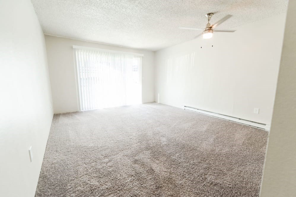 an empty living room with carpet and a ceiling fan
