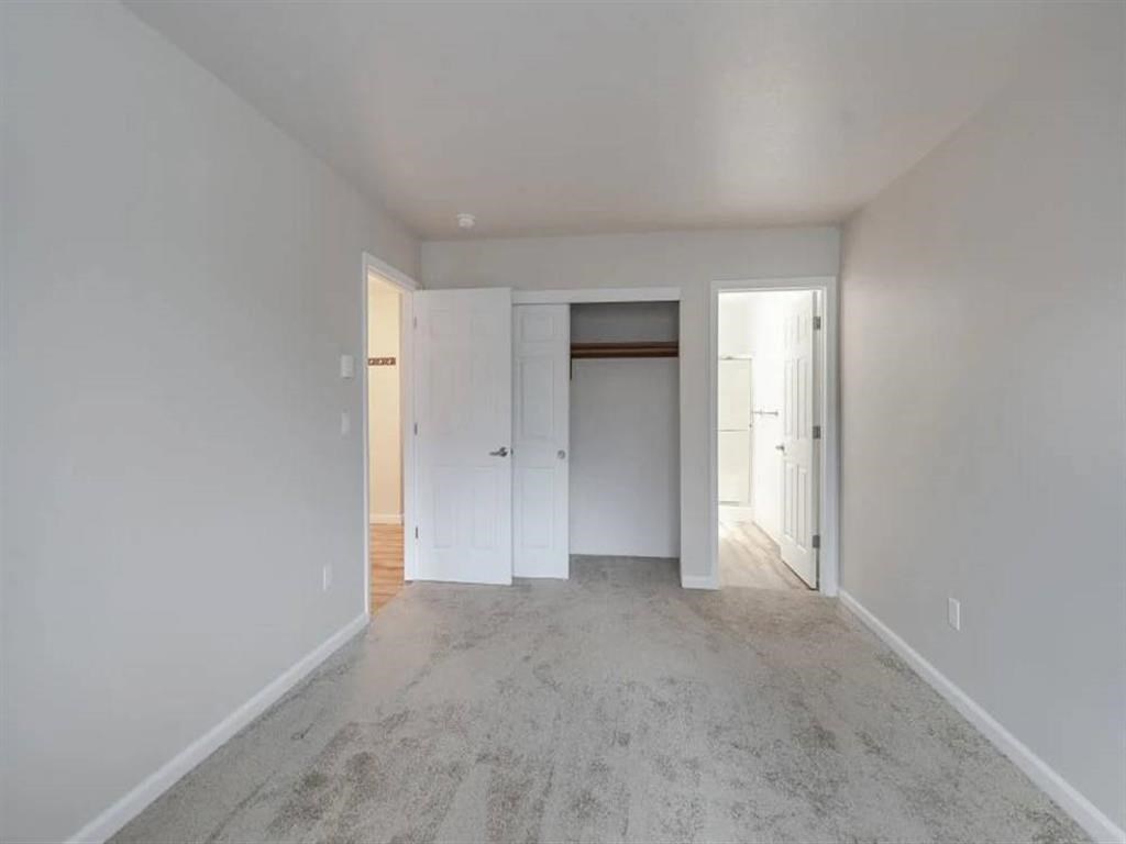 an empty living room with white walls and a door to a closet