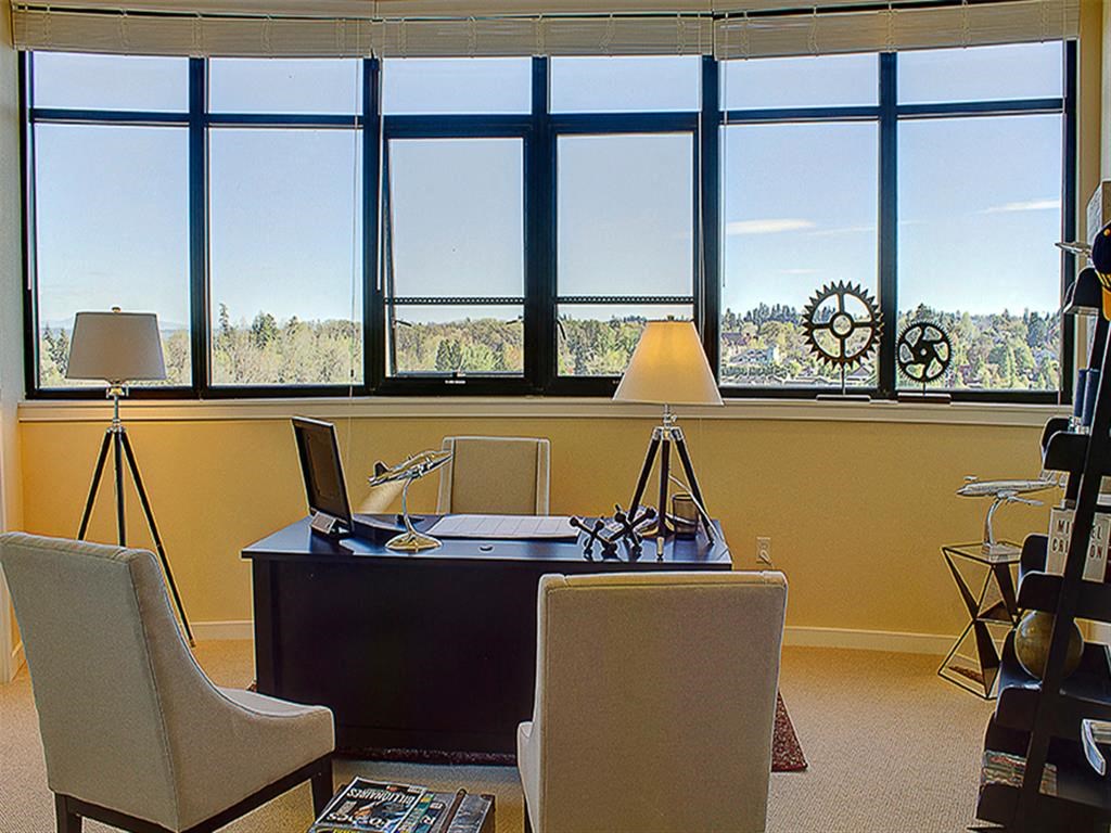 a desk with a laptop and chairs in front of a window