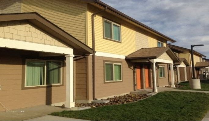 a row of houses with yellow siding and green windows