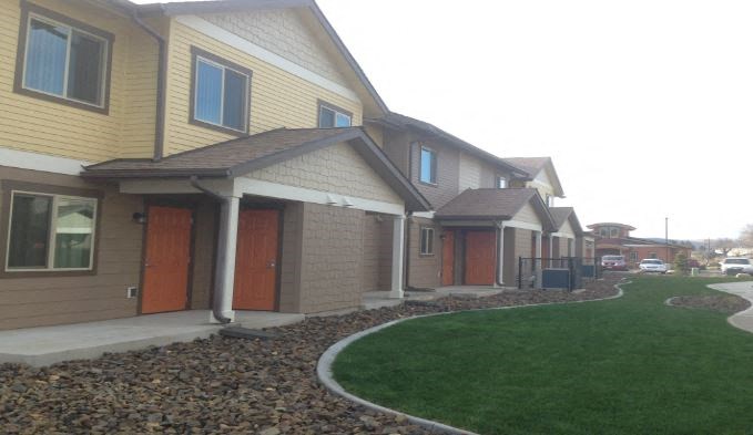 a row of houses with green grass outside of them